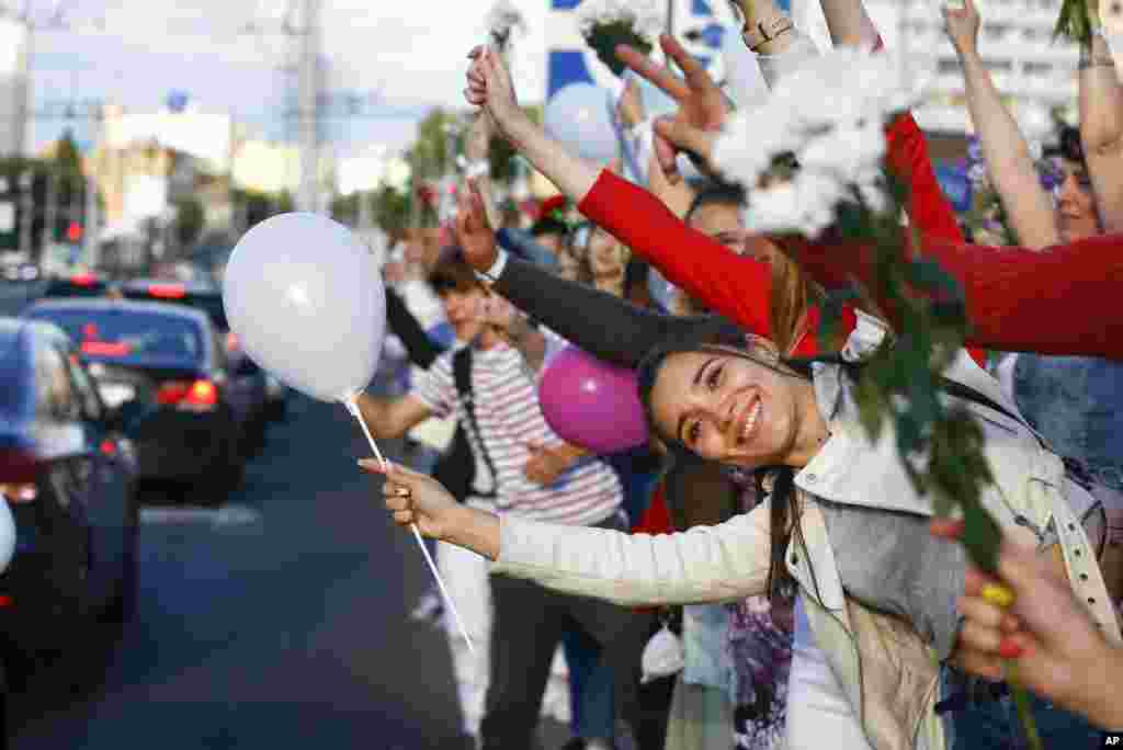 People wave flowers as they gather to protest against the results of the country&#39;s presidential election in Minsk, Belarus.