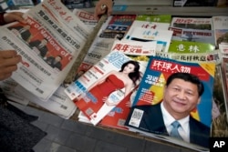 北京报摊上的报纸刊物，其中《环球人物》杂志的封面上有习近平照片和《习近平 中国强起来》的标题，还有报道中共十九大修改党章消息的北京晚报，也有以影视明星范冰冰为封面的《知音》杂志。（2017年10月21日）