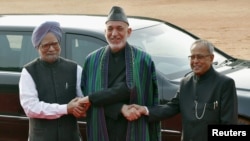 Afghanistan's President Hamid Karzai (C) shakes hands with his Indian counterpart Pranab Mukherjee (R) and Indian PM Manmohan Singh during a ceremonial reception in New Delhi, November 12, 2012. 