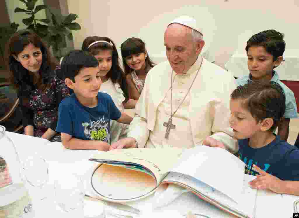 프란치스코(가운데) 교황이 그리스 레스보스 섬에서 온 시리아 난민 어린이들과 점심을 함께 먹은 뒤 그림책을 보면서 웃음짓고 있다.