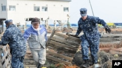 US sailors help remove debris during a cleanup effort at Japan's Misawa Fishing Port on March 14, 2011.