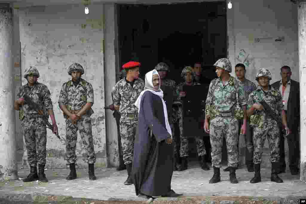 An Egyptian man passes by a polling station as soldiers stand guard, in the town of Ibshawai, near Fayoum, 100 km (62 miles) southwest of Cairo, November 29, 2011. (AP)
