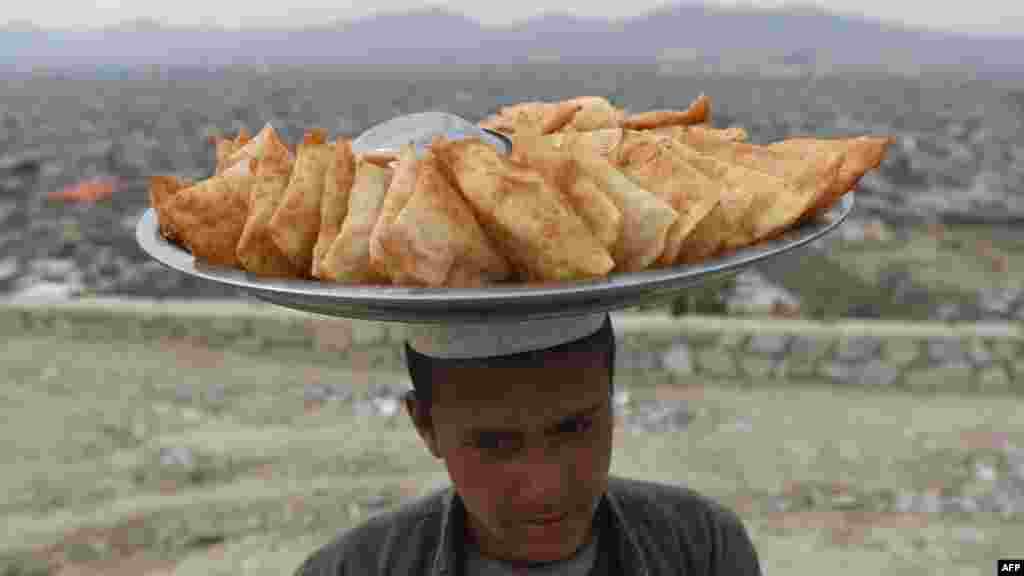 아프가니스탄 카불의 언덕에서 아프간 소년이 사모사(감자와 채소, 커리 등을 넣은 삼각형 모양의 튀김​)을 팔고 있다.