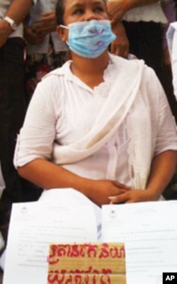 A woman, dressed in white, display documents from the land dispute.