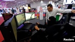 A Saudi woman tries a car simulator during a car show in Riyadh, May 13, 2018.