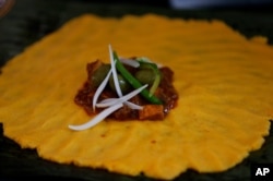 FILE - This photo shows the inner ingredients of a hallaca, a corn dough tamale, during its preparation at a Christmas fair in a state-owned market in Caracas, Venezuela, Nov. 23, 2013.