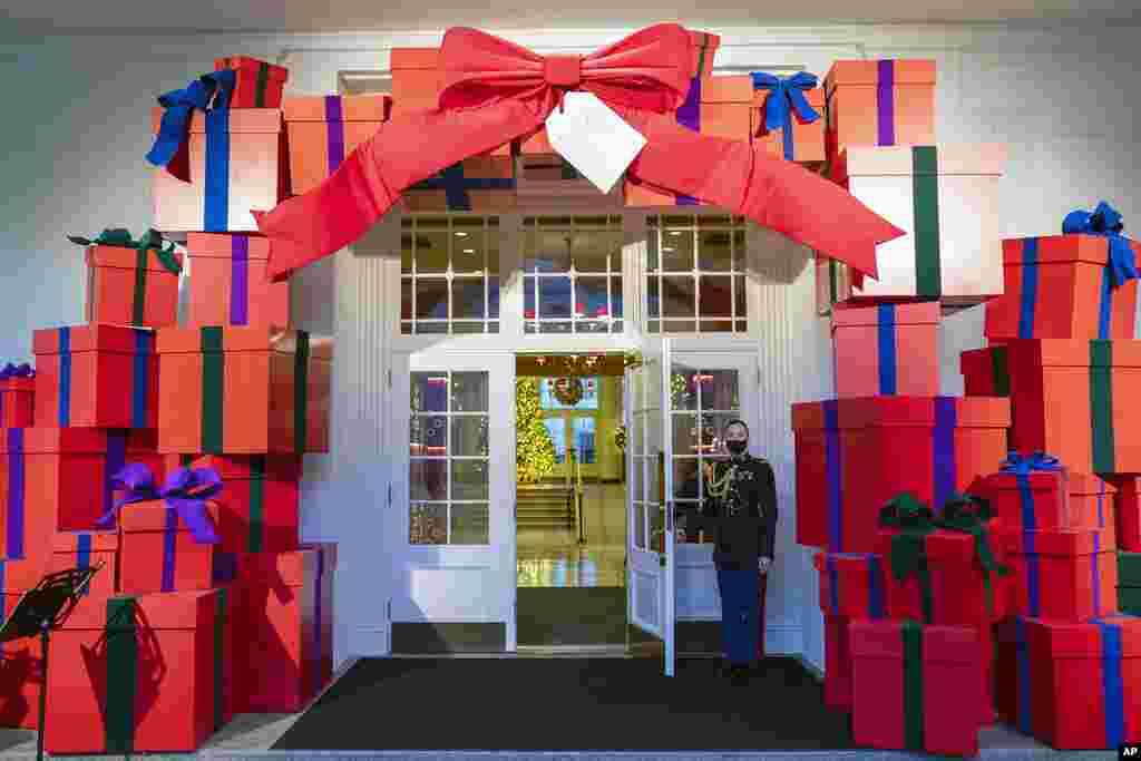 A Marine White House Military social aide holds the door to the East Wing entrance of the White House during a press preview of the White House holiday decorations, Nov. 29, 2021.