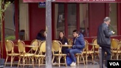 People sit outside the Carillon bar, one of the targets of the November 13 attacks. (L. Bryant/VOA)