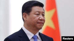 FILE - China's President Xi Jinping stands next to a Chinese national flag during a welcoming ceremony at the Great Hall of the People, in Beijing, Nov. 13, 2013.