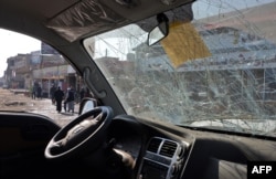 Iraqis are seen through a damaged car in Mosul, Iraq, Nov. 9, 2018. A car bomb that killed three people and wounded a dozen on Nov. 8, 2018.