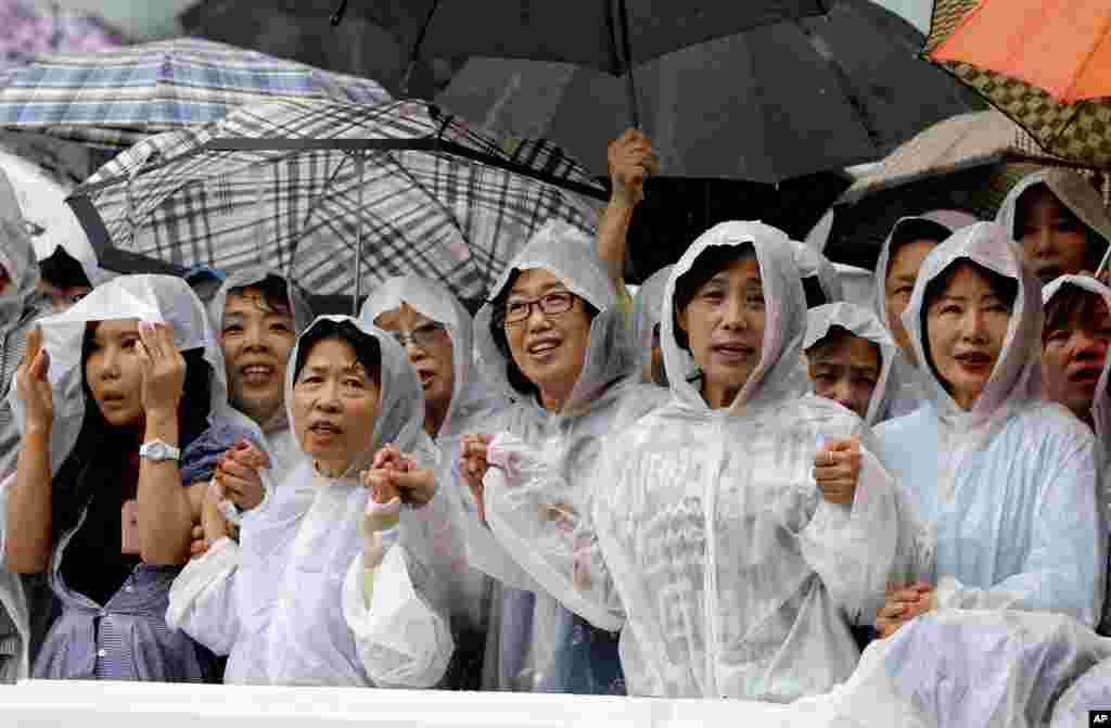 Umat menyanyikan lagu reunifikasi dalam Misa untuk perdamaian dan rekonsiliasi di luar Katedral Myeongdong di Seoul, Korea Selatan (18/8). (AP/Ahn Young-joon)