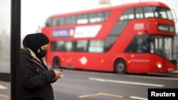 Seorang perempuan menggunakan ponselnya di halte bus di tengah wabah COVID-19 di London, Inggris (foto: ilustrasi). 