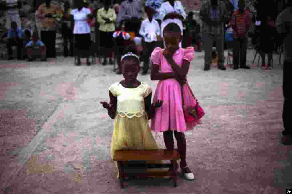 Smeralda, 12, kneeling, and her sister Serena, 11, pray during mass next to the rubble of the Notre Dame Cathedral in Port-au-Prince, Haiti, Sunday Nov. 14, 2010. (AP Photo/Emilio Morenatti)