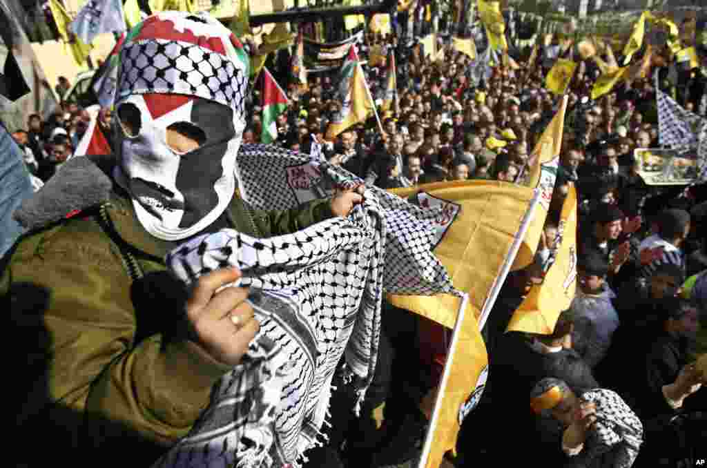 A masked Palestinian holds a traditional Arab headdress during Fatah anniversary celebration in the West Bank city of Nablus, January 3, 2013.