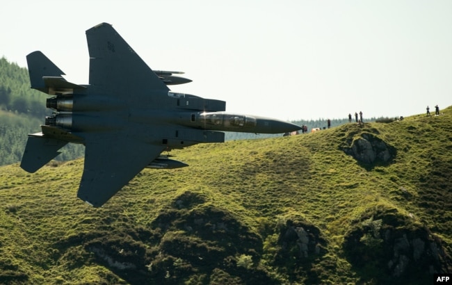 Military aircraft enthusiasts watch as a United States Air Force (USAF) F-15 fighter jet as it travels at low altitude through the 'Mach Loop' series of valleys near Dolgellau, north Wales on June 26, 2018.