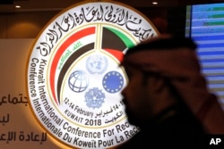 A Kuwaiti official stands in front of an illuminated sign for a conference on Iraq being held in Kuwait City, Kuwait, Feb. 12, 2018.