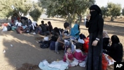 Newly-arrived Syrian refugee families rest after having crossed the border from Tal Shehab in Syria, through the Al Yarmouk River valley, to near Ramtha, Jordan, Sept. 15, 2012.