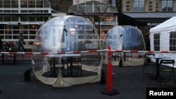 Pedestrians walk past temporary tents and structures erected outside of restaurants meant for outdoor dining in Washington, U.S. November 24, 2020. (REUTERS/Leah Millis)