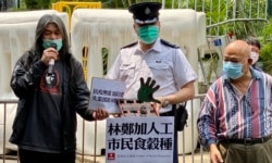 社民連前立法會議員梁國雄(左一）向警方代表遞交請願信及諷刺特首林鄭月娥封關等防疫措施”彈弓手“的示威道具。（美國之音湯惠芸攝）