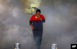 A Maldivian opposition protester demanding the release of political prisoners is engulfed in tear gas fired by police during a protest in Male, Maldives, Feb. 2, 2018.