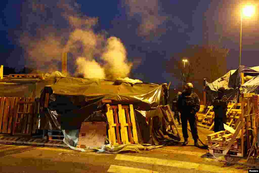 Policemen stand guard before clearing a yellow vests camp at a traffic island near the A2 Paris-Brussels motorway in Fontaine-Notre-Dame, France.