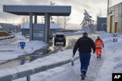 Truck drivers with customs clearance documents walk toward the Norwegian Customs office at the Orje border as officers perform checks on cars entering from Sweden, Feb. 8 2019.