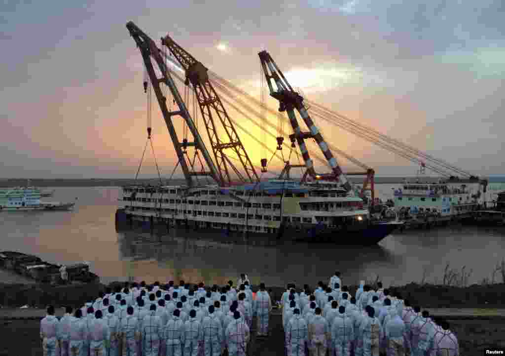 Para pekerja penyelamat berbaris di pinggir sungai saat kapal pesiar Eastern Star yang tenggelam ditarik keluar Yangtze di Jianli, provinsi Hubei, China.