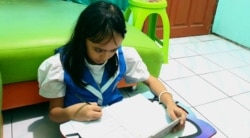 Seorang pelajar SD sedang mengerjakan ujian dari rumah di masa pandemi corona, di Surabaya, 12 Mei 2020. (Foto: Petrus Riski/VOA)