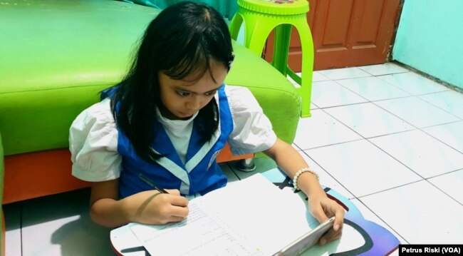 Seorang pelajar SD sedang mengerjakan ujian dari rumah di masa pandemi corona, di Surabaya, 12 Mei 2020. (Foto: Petrus Riski/VOA)