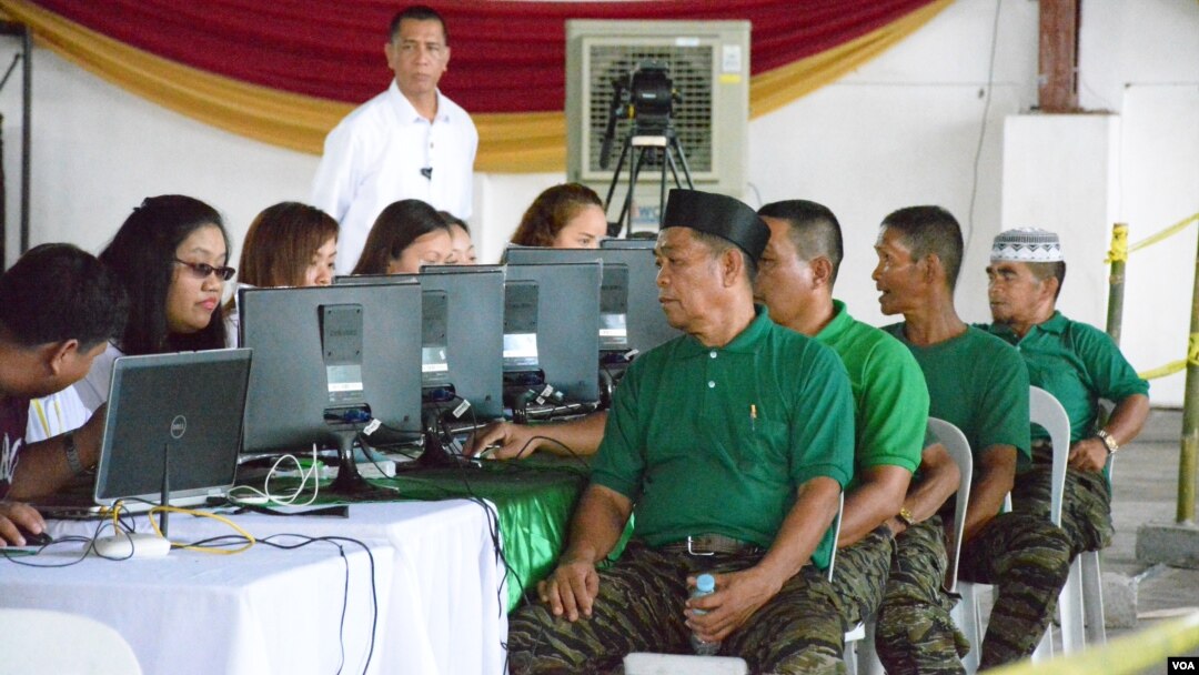 Jacob Palao (front), a rebel deputy commander, gets processed for livelihood assistance for Moro Islamic Liberation Front fighters, in Sultan Kudarat, Maguindanao Province, the Philippines, June 16, 2015. (VOA/Simone Orendain)