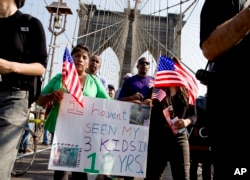 FILE - Martha Gualotuna of New York, center left, walks across New York's Brooklyn Bridge during a march and rally highlighting immigration reform, Oct. 5, 2013. Gualotuna is one of the 4 million immigrants who would have benefited from a program that was blocked June 23, 2016, by a decision of the Supreme Court.