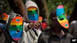 Kenyan gays and lesbians and others supporting their cause wear masks to preserve their anonymity and one holds out a wrapped condom, as they stage a rare protest, against Uganda's increasingly tough stance against homosexuality and in solidarity with their counterparts there, outside the Uganda High Commission in Nairobi.