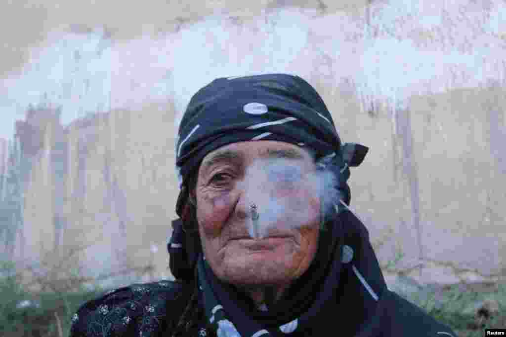 Seorang perempuan beristirahat sambil merokok setelah dievakuasi oleh Pasukan Demokratis Suriah (SDF) dari kota Manbij yang dikuasai ISIS di Aleppo, Suriah (12/8). (Reuters/Rodi Said)