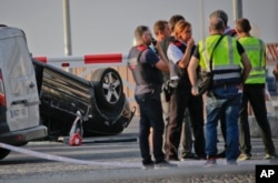 Police officers speak near an overturned car at the spot where terrorists were intercepted by police in Cambrils, Spain, Aug. 18, 2017.