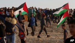 Protesters gather as others wave their national flag as they lie near the border fence between the Gaza Strip and Israel during a demonstration on the beach near Beit Lahiya, in the northern Gaza Strip, November 19, 2018.