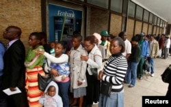 People queue to withdraw cash outside a bank in Harare, Zimbabwe, Nov. 28, 2017.