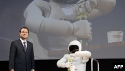 Pemimpin perusahaan Honda Motor Co. Takanobu Ito berdiri di dekat robot "Asimo" saat menggelar konferensi pers dalam Tokyo Motor Show, Jepang tahun 2011 (Foto: dok). Takanobu Ito, akan mundur dari posisinya sebagai direktur perusahaan tersebut, menyusul kemelut skandal kantong udara mobil yang buruk, Senin (23/2).