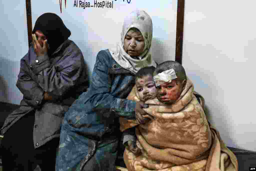Seorang perempuan Suriah duduk sambil memeluk dua anaknya yang terluka di sebuah rumah sakit, pasca serangan pasukan pemerintah terhadap distrik Barzah, di pinggiran ibukota Damaskus.