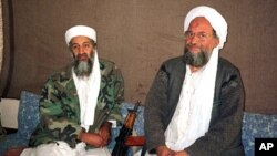 អូសាម៉ា​ប៊ិន​ឡាដិន (Osama bin Laden) (ឆ្វេង) អង្គុយ​ជាប់​នឹង​ អាយមែន អា ហ្សារ៉ាហ៊ីរី (Ayman al-Zawahri) ដែល​ជា​​ប្រធាន​ខាង​យុទ្ធសាស្ត្រ​របស់​អង្គការ​អាល់កៃដា និង​ជា​មេបញ្ជាការ​លំដាប់​ទី​២ នៅក្នុង​រូបថត​ឆ្នាំ​២០០១​នេះ។