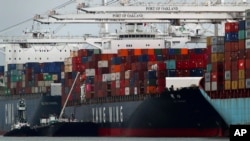 The Yang Ming shipping line container ship Ym Utmost is unloaded at the Port of Oakland on Monday, July 2, 2018, in Oakland, Calif. The Trump administration on Friday, July 6, 2018, started imposing tariffs on $34 billion in Chinese imports. China responded with retaliatory tariffs.