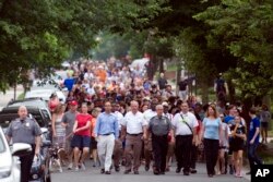 People walk to a church to say a prayer near the baseball field, the scene of a multiple shooting in Alexandria, Va., Wednesday, June 14, 2017.