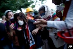 FILE - In this June 11, 2013, photo, a protester affected by tear gas is helped by other protesters to a field hospital in Gezi Park in Taksim Square in Istanbul, Turkey.