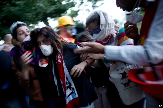 FILE - In this June 11, 2013, photo, a protester affected by tear gas is helped by other protesters to a field hospital in Gezi Park in Taksim Square in Istanbul, Turkey.