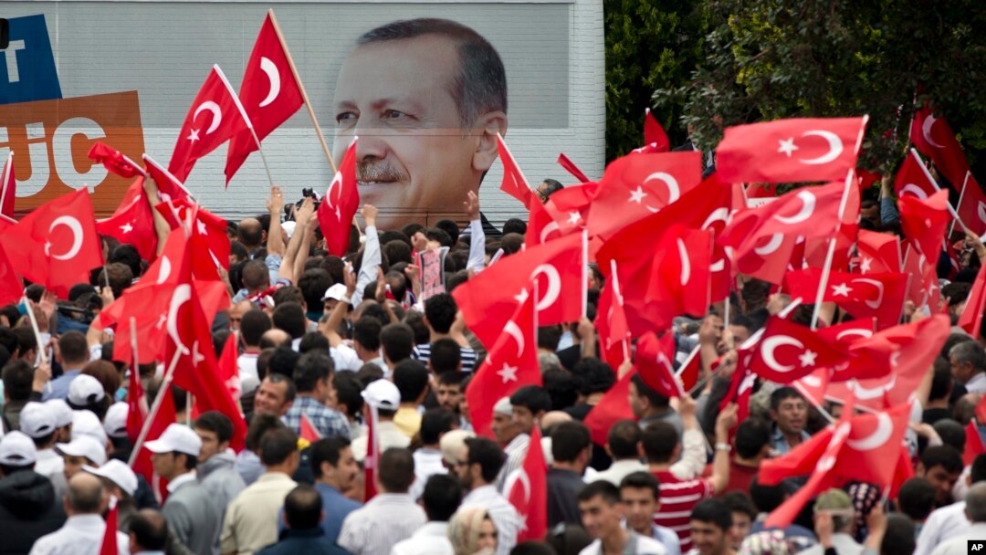 Para pendukung melambai-lambaikan bendera Turki dengan latar belakang gambar Perdana Menteri Recep Tayyip Erdogan saat mereka menunggu kedatangannya di Ankara (9/6).