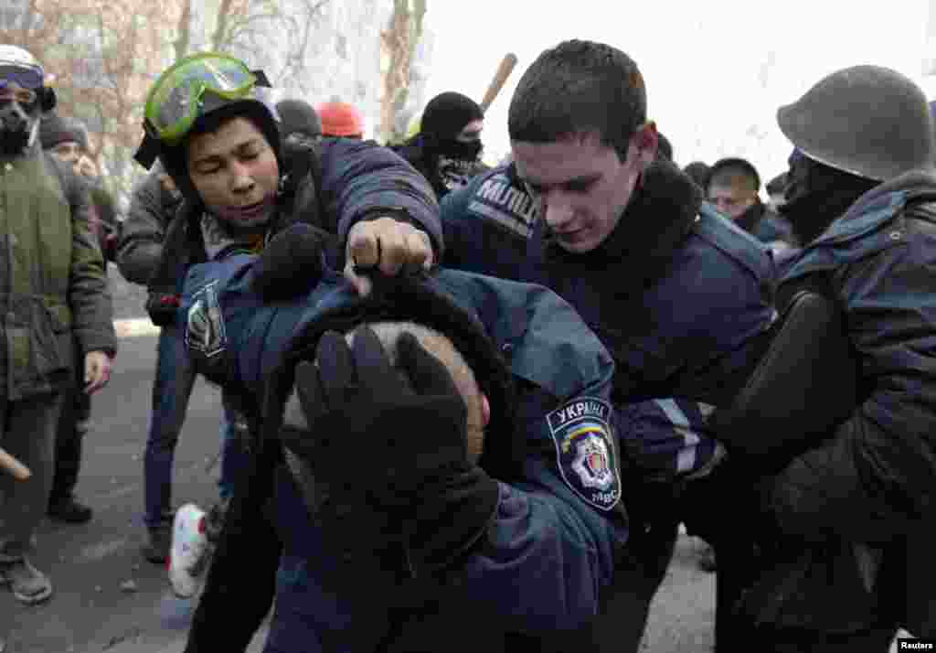 Manifestantes escoltam elementos do Ministério do Interior depois de atacarem o edifício do Partido das Regiões, Kiev, Fev. 18, 2014. 
