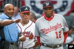 Washington Nationals manager Dusty Baker (12) and Atlanta Braves manager Brian Snitker meet with umpire C.B. Bucknor before a baseball game, April 18, 2017, in Atlanta.