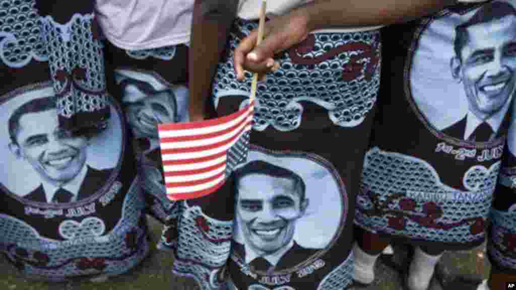 A woman wearing a skirt with the face of President Obama holds an American flag.