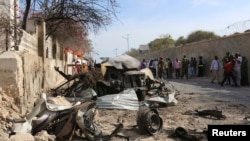 FILE - People look at the scene of a suicide attack by al-Qaida-linked militants of al-Shabab, next to the gate of the Presidential Palace in Mogadishu, February 2014.