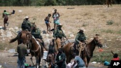 U.S. Customs and Border Protection mounted officers attempt to contain migrants as they cross the Rio Grande from Ciudad Acuña into Del Rio, Texas, Sept. 19, 2021.