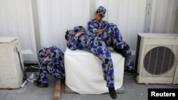 Security personnel take a nap behind one of the halls of Auto China 2016 auto show in Beijing April 25, 2016. 